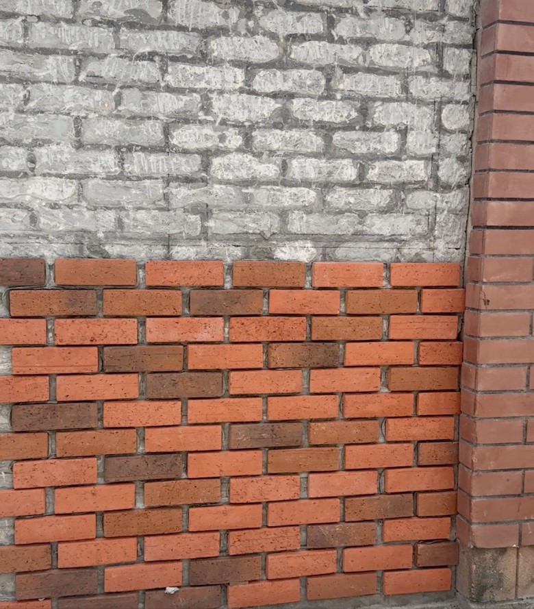 Brick veneer units being fixed to a rendered wall with tile adhesive.
